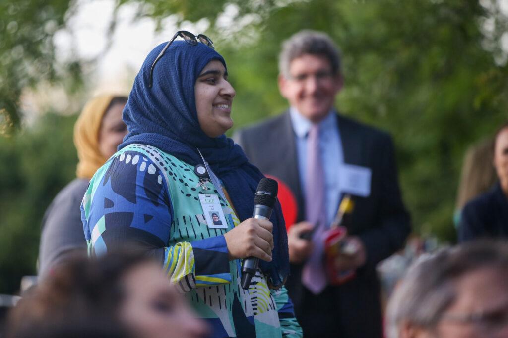 A Discovering Justice fellow smiles while holding a microphone